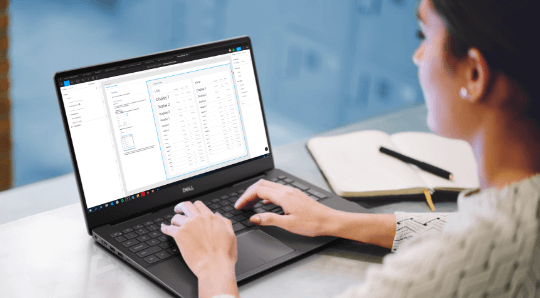 A woman sitting in a desk using a Dell laptop with the DDS Figma file showing the font ramp of the Dell Design System. Next to her laptop there is a sketchbook with a pen on top of it.